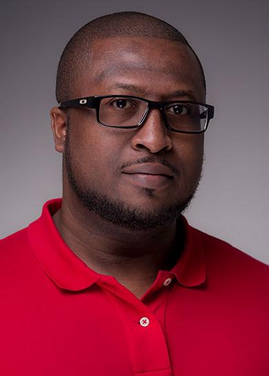 An African American male with a beard, Dederick Scott wears a red collared polo and black rimmed glasses.